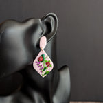 Handcrafted light pink floral earrings with red blooms, green leaves, and small pink flower accents.