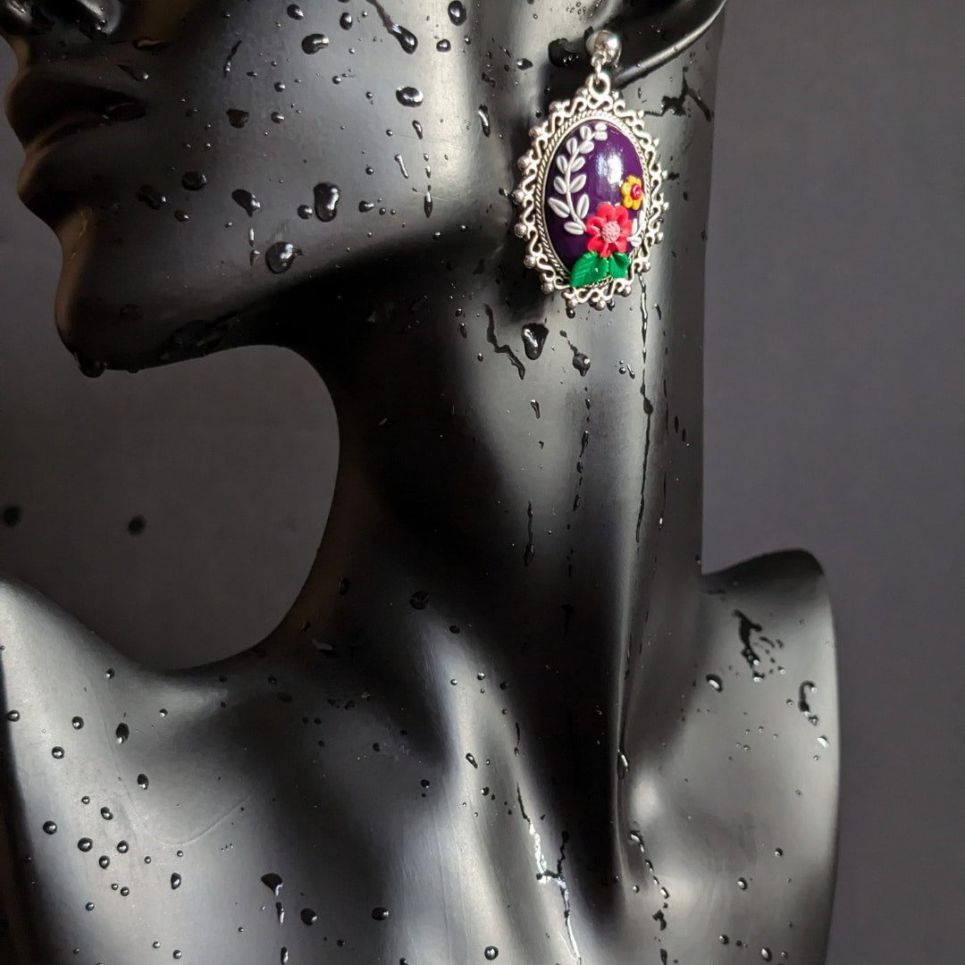 Radiant Floral Embrace Earrings with oxidized silver bezel, purple clay base, and detailed floral designs.