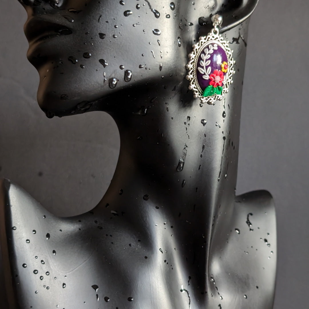 Radiant Floral Embrace Earrings with oxidized silver bezel, purple clay base, and detailed floral designs.