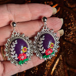 Radiant Floral Embrace Earrings with oxidized silver bezel, purple clay base, and detailed floral designs.