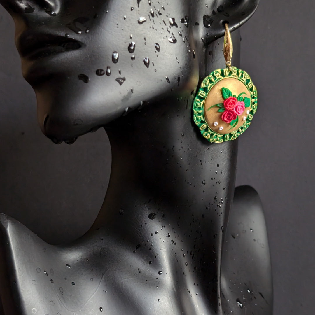 Handcrafted floral medallion earrings with green bezel and golden center adorned with roses and leaves.