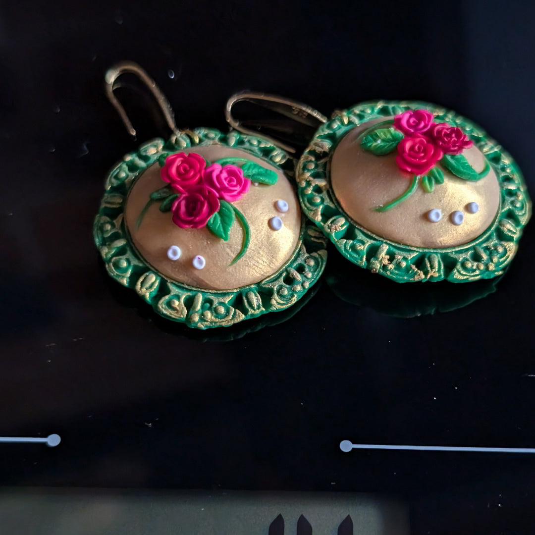 Handcrafted floral medallion earrings with green bezel and golden center adorned with roses and leaves.