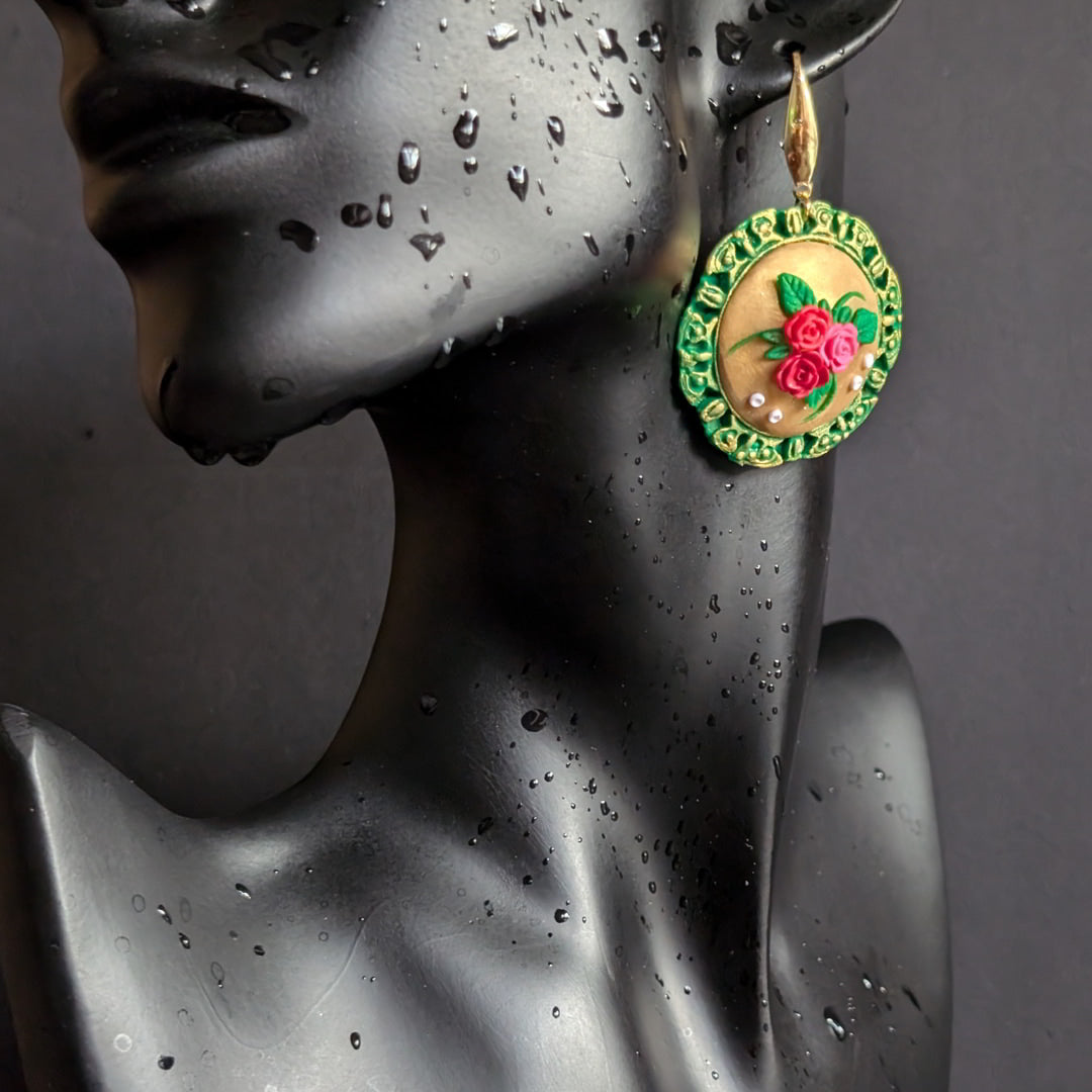 Handcrafted floral medallion earrings with green bezel and golden center adorned with roses and leaves.