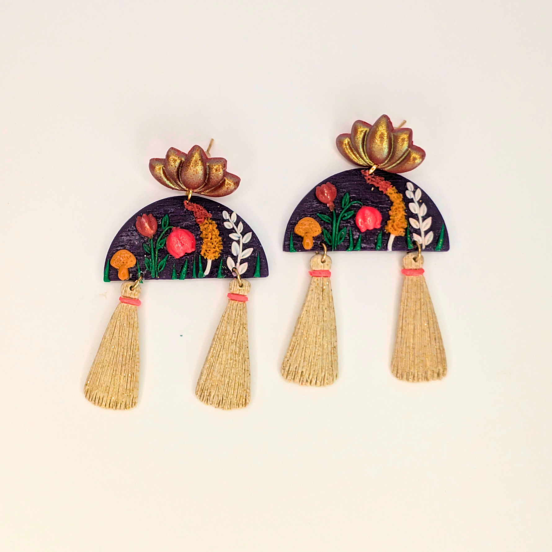 Handcrafted Blooming Lotus Tassel Earrings with red and orange flowers, green leaves, golden accents, and a purple half-moon base