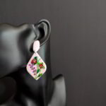 Handcrafted light pink floral earrings with red blooms, green leaves, and small pink flower accents.