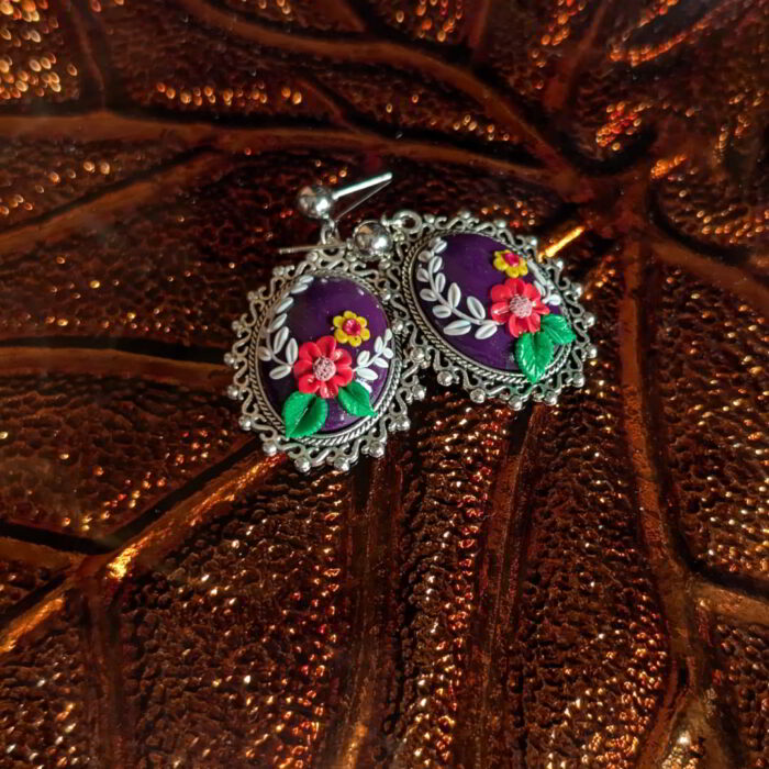 Radiant Floral Embrace Earrings with oxidized silver bezel, purple clay base, and detailed floral designs.